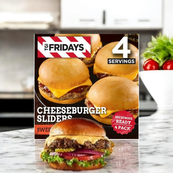 A box of TGIF Fridays Cheeseburger Sliders with Sweet & Smoky BBQ Sauce Frozen Food Snacks-3 Count is on the kitchen counter with fresh vegetables, offering a tasty snack option.