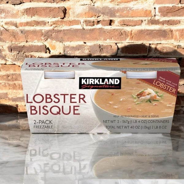 A Kirkland Signature Lobster Bisque box is set against a brick wall, showcasing it as a creamy seafood soup available in a 2-pack of 40 oz containers.