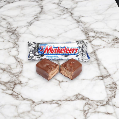 A package of Mars Fun Size 3 Musketeers - 5 Count Fun Size Bars is displayed on a marble surface. One of the fun-sized bars is partially unwrapped, with one piece cut in half to reveal the whipped chocolate filling inside.