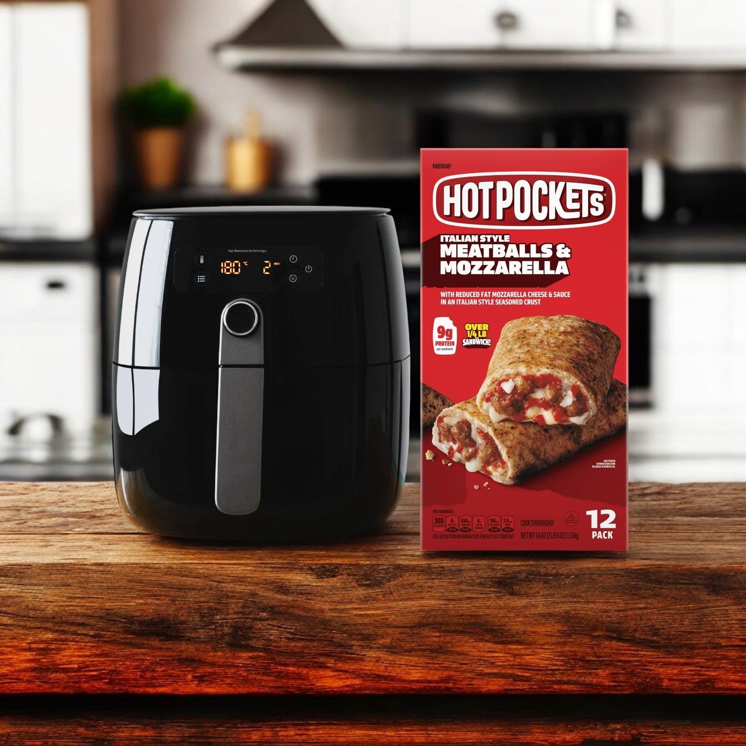 A black air fryer and a box of Hot Pockets Frozen Snacks, Meatballs and Mozzarella Cheese from Hot Pockets are on a wooden kitchen counter, with a modern kitchen in the background.