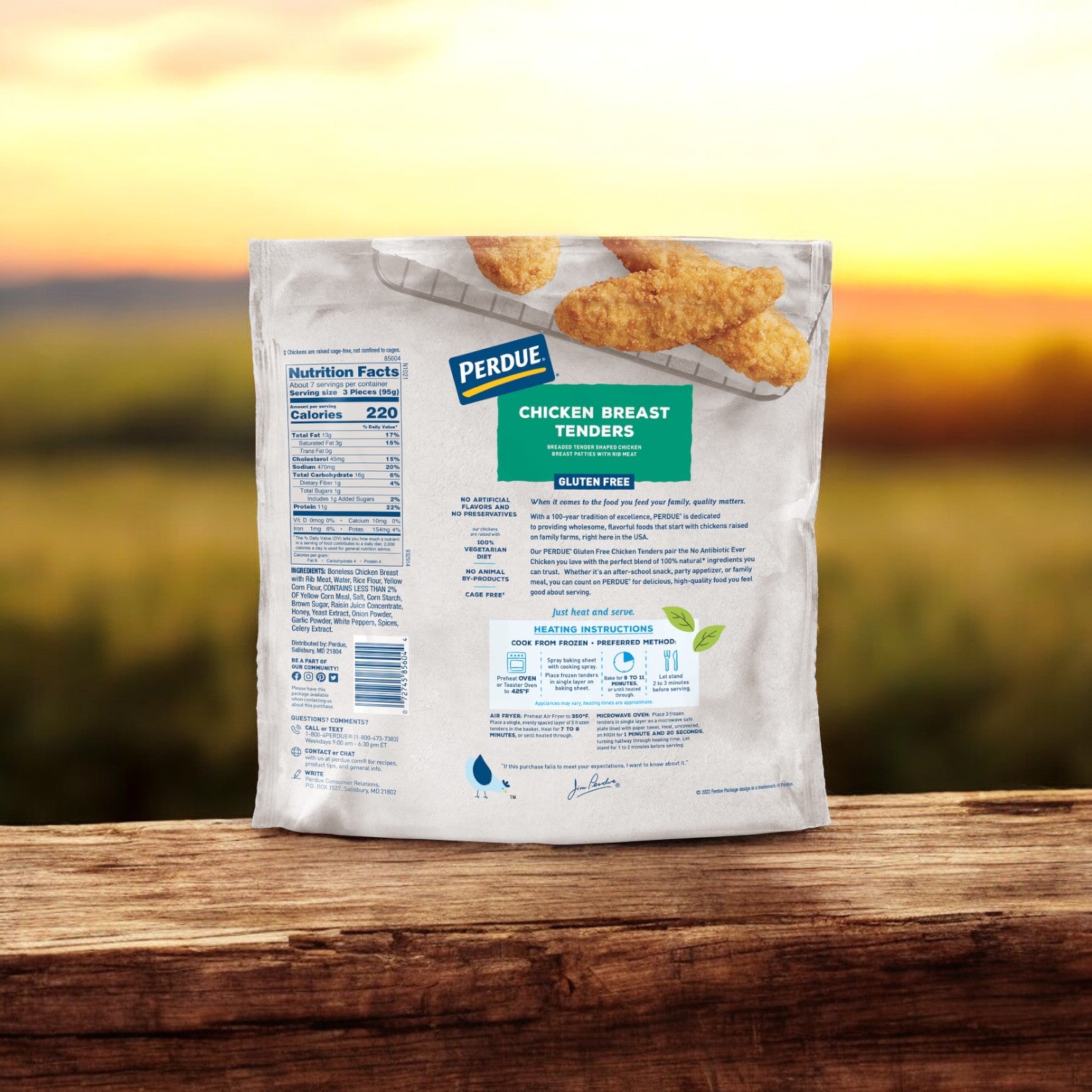 A bag of Perdue Breaded Chicken Breast Tenders Gluten Free, weighing 22 oz., rests on a wooden surface. The packaging highlights nutritional details and cooking instructions, set against a calming blurred outdoor background at sunset.