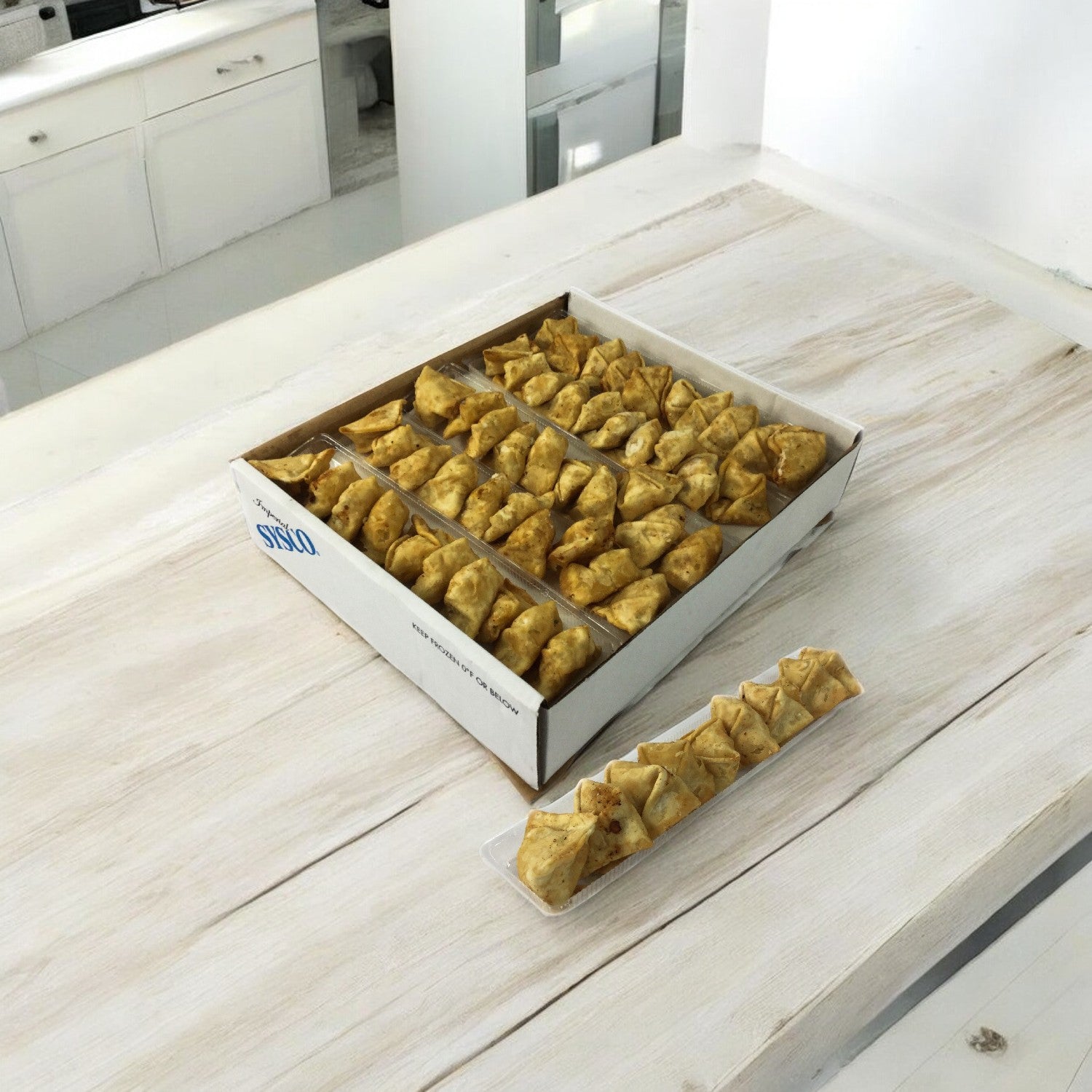 A light wooden table displays a box of triangular pastries and a smaller tray with several Crab Rangoon from Sysco's 100-count appetizer case, featuring free shipping.