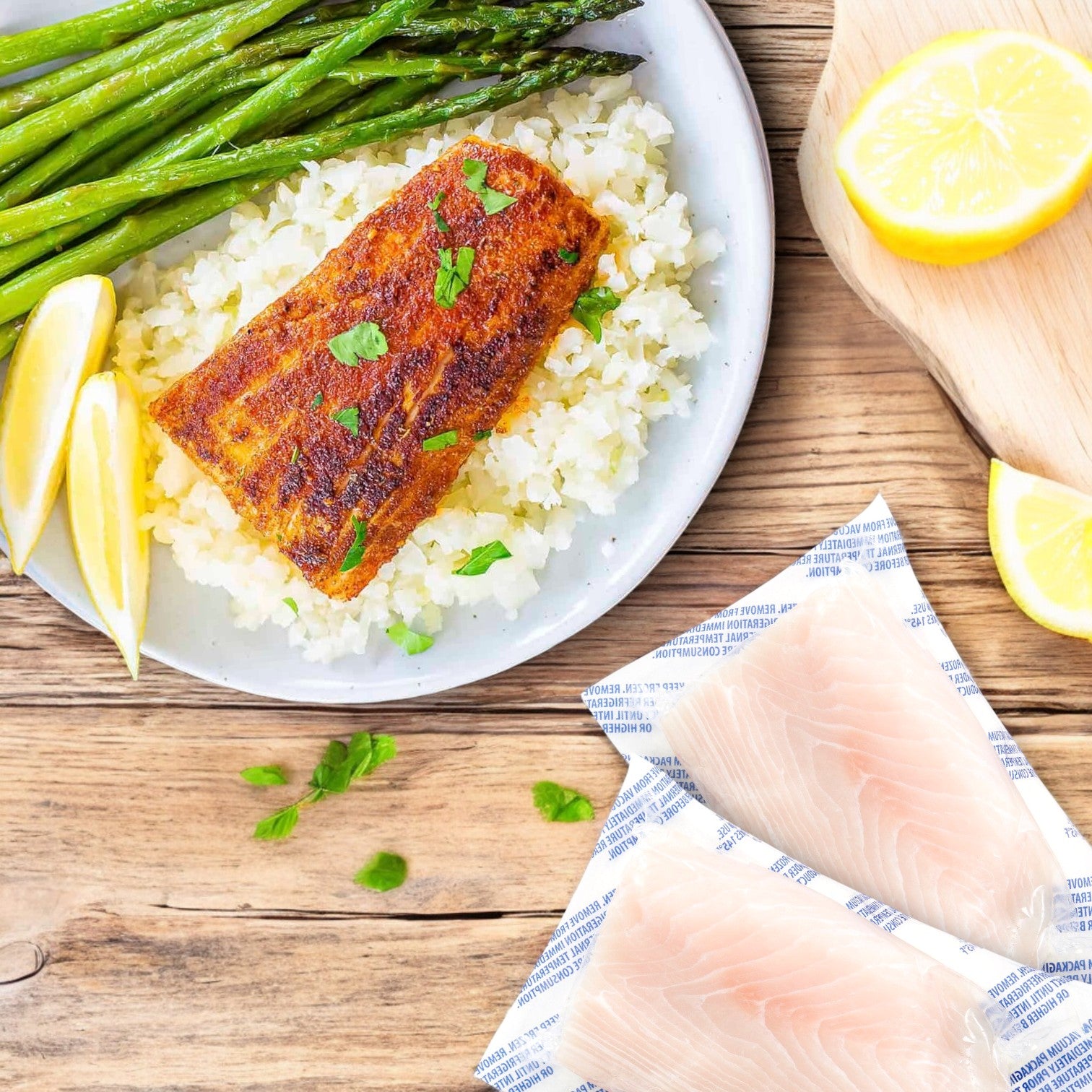 Portico Classic Seafood Mahi Mahi portions are grilled and served on seasoned rice with asparagus and lemon wedges. Raw fillets and halved lemon await on a wooden surface, ready for preparation.