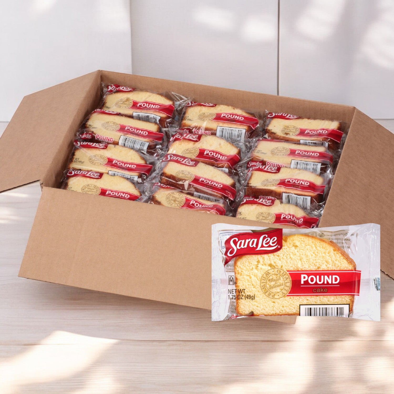 An open box containing 24 individually wrapped Sarah Lee Pound Cake slices, each 1.75 oz., is displayed on a light wood surface, highlighting their buttery flavor and irresistibly moist texture.