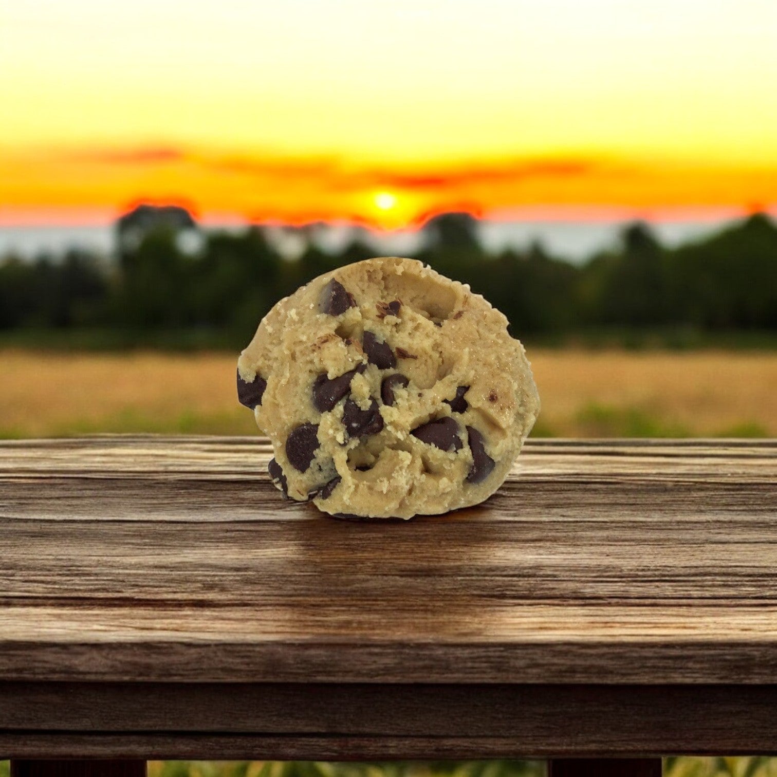 A ball of David's Cookies Dough Cookie - Chocolate Chip (Raw, 80/4 oz) sits on a wooden surface, ready to bake into delicious cookies as the sun sets.