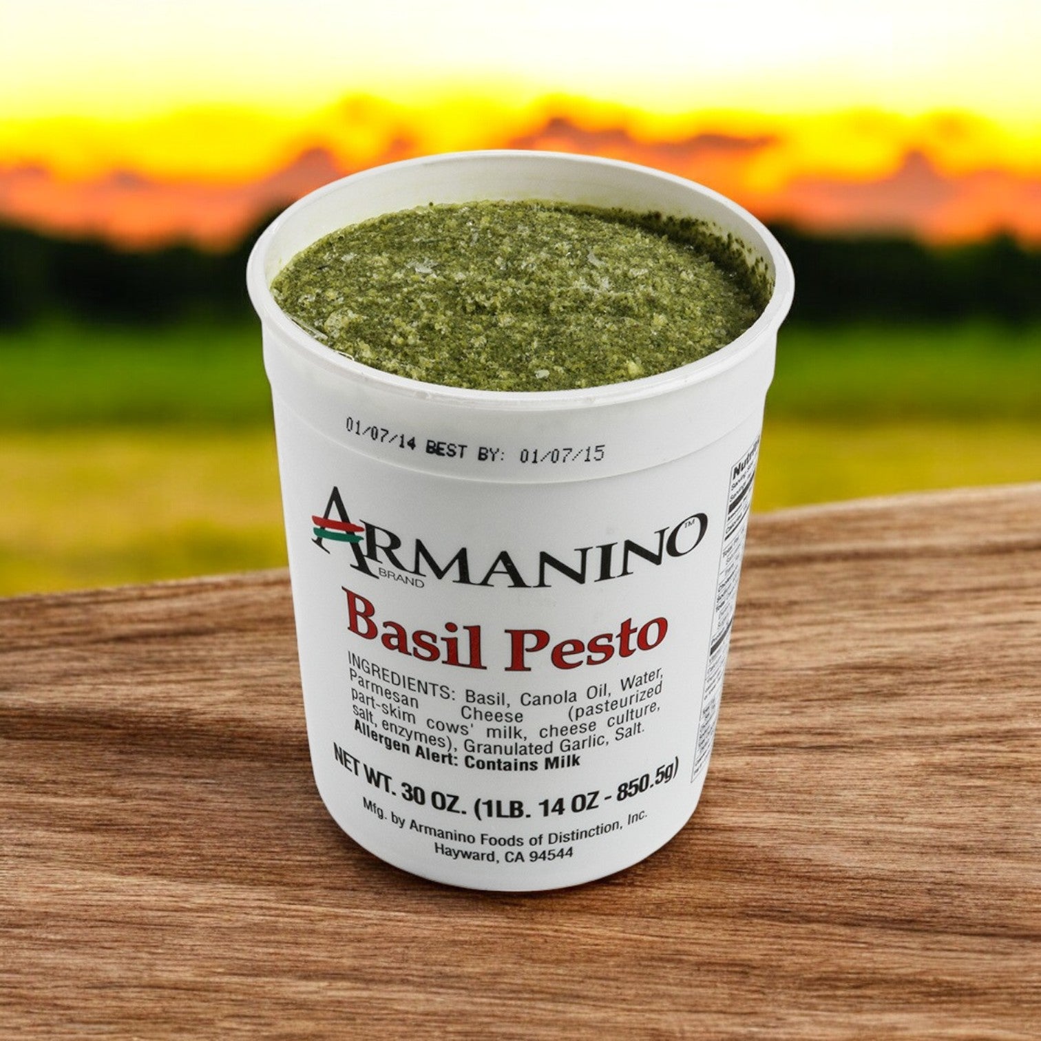 A 30 oz pack of Armanino Pesto Sauce-Farms Pesto Basil Sauce, rich in authentic Italian flavor, rests on a wooden surface against an outdoor backdrop.