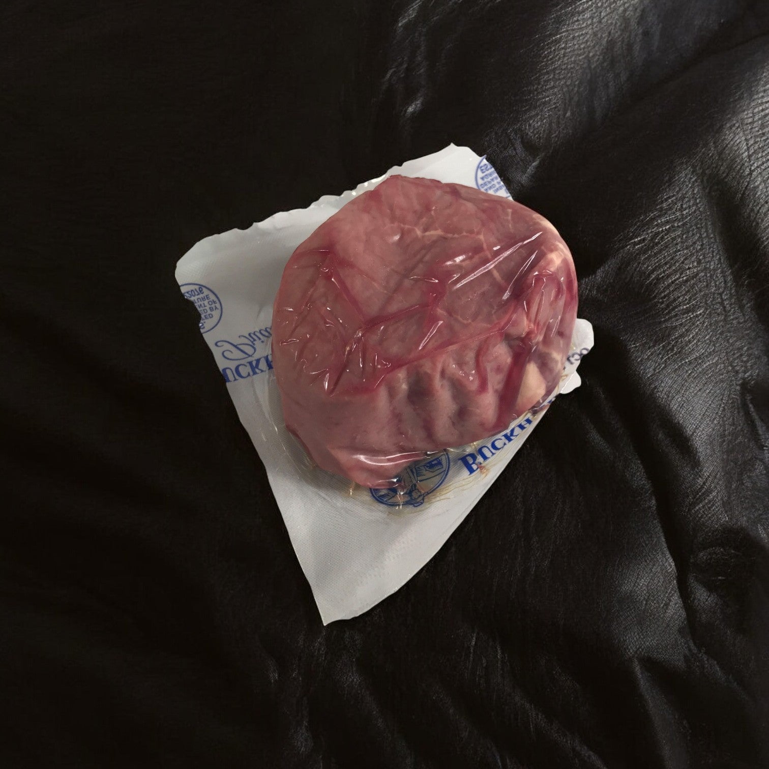 A case of Buckhead Pride/Newport Pride Steak Filet Center-Cut, featuring 28 six-ounce cuts with a buttery-smooth texture, rests in a labeled plastic wrapper on a dark surface.