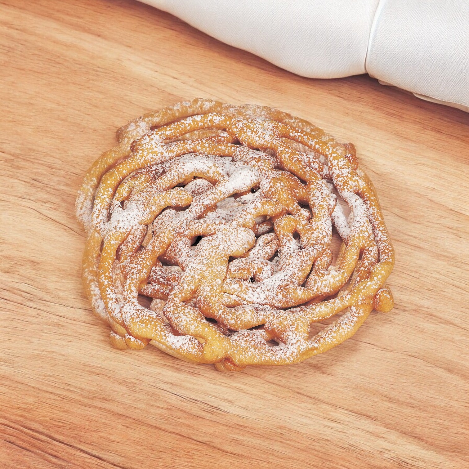 An 8.5-inch J&j Snacks Funnel Cake from a 24 count pack, that classic sweet treat, sits on a wooden surface dusted with powdered sugar.