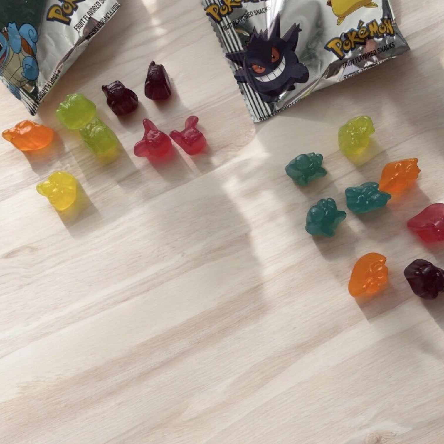 Unwrapped General Mills Pokémon Gluten Free Fruit Flavored Snack Treat Pouches on a light wooden surface, showcasing an assortment of colorful and uniquely shaped gummy figures, ideal for on-the-go convenience.