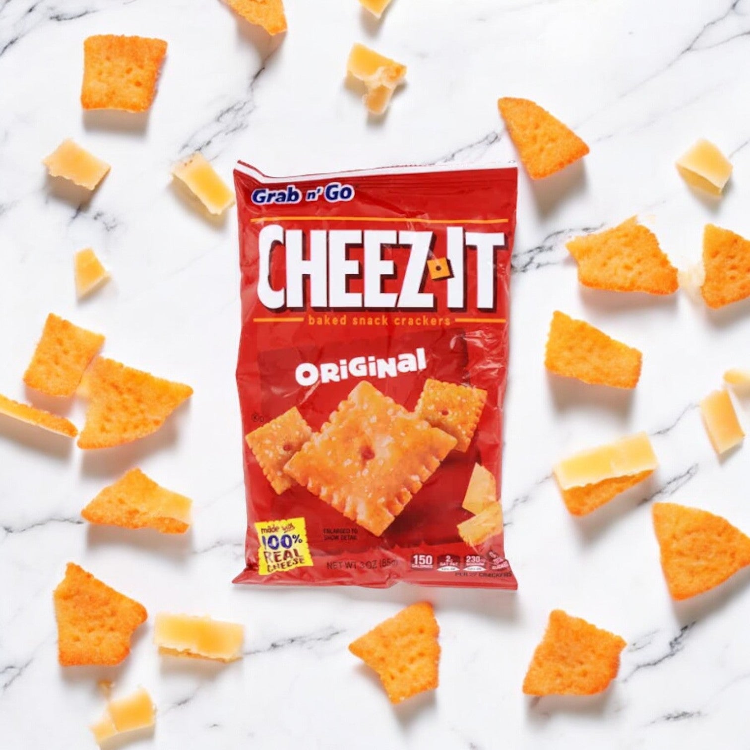 A bag of Kellogg's Cheez-It Crackers, Cheddar, 1.5 oz, labeled as a Kosher snack and made with real cheese, surrounded by scattered pieces of the crackers on a white marble surface.