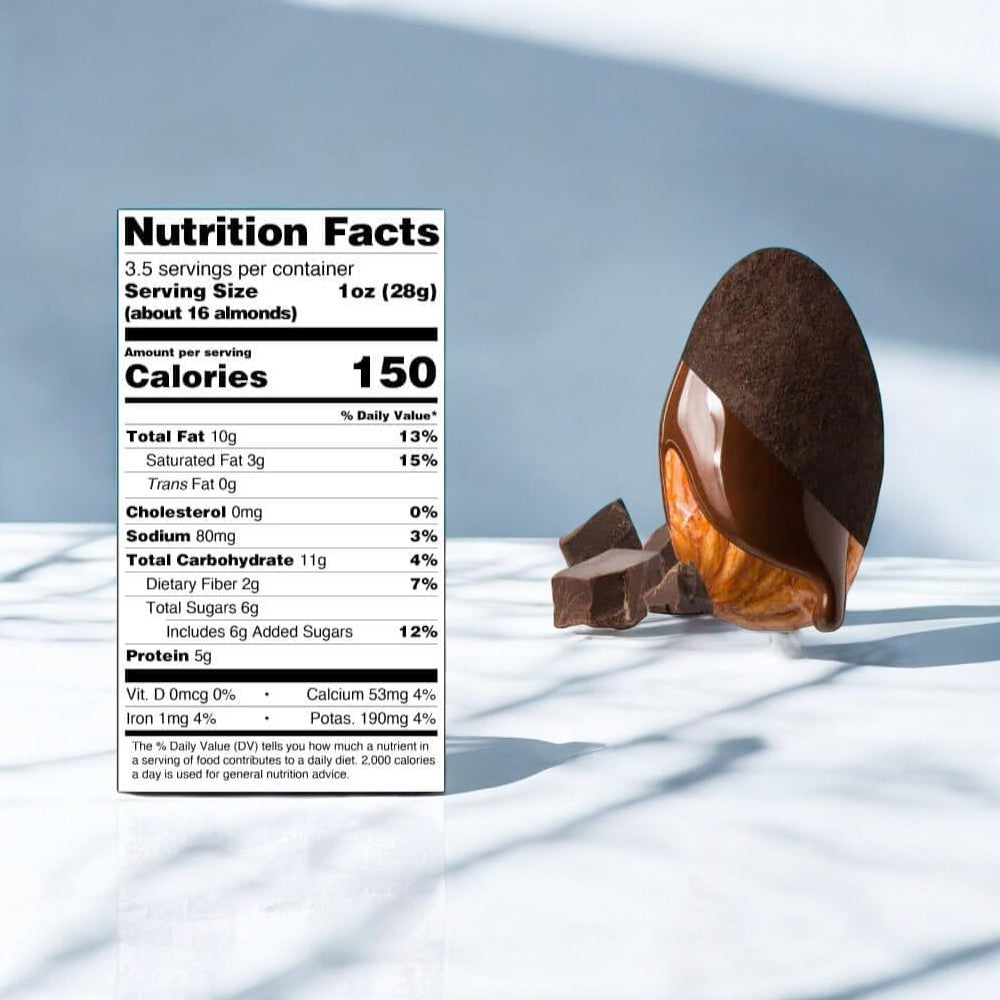 A large almond, enrobed in a dark chocolate shell, sits next to several pieces of Skinny Dipped Dark Chocolate Candy Cocoa Almonds from a 3 oz bag. The accompanying nutritional information label emphasizes this healthy snack option.