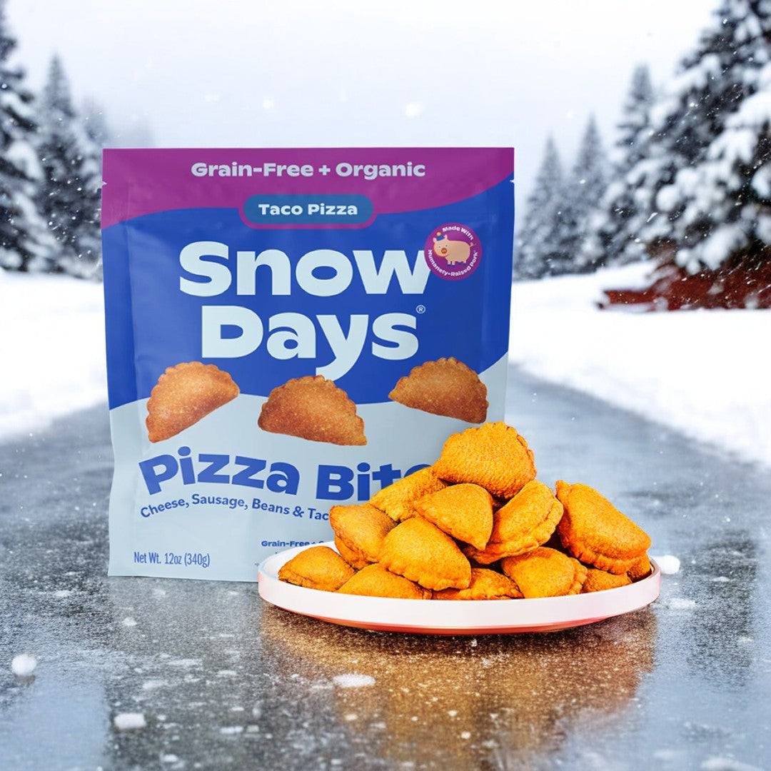 A package of Snow Days Frozen Organic Taco Pizza Bites, featuring cheese, sausage, beans, and taco seasoning, rests on a snowy road next to a plate of these adaptable snacks, delivering an exceptional flavor blend ideal for any craving.