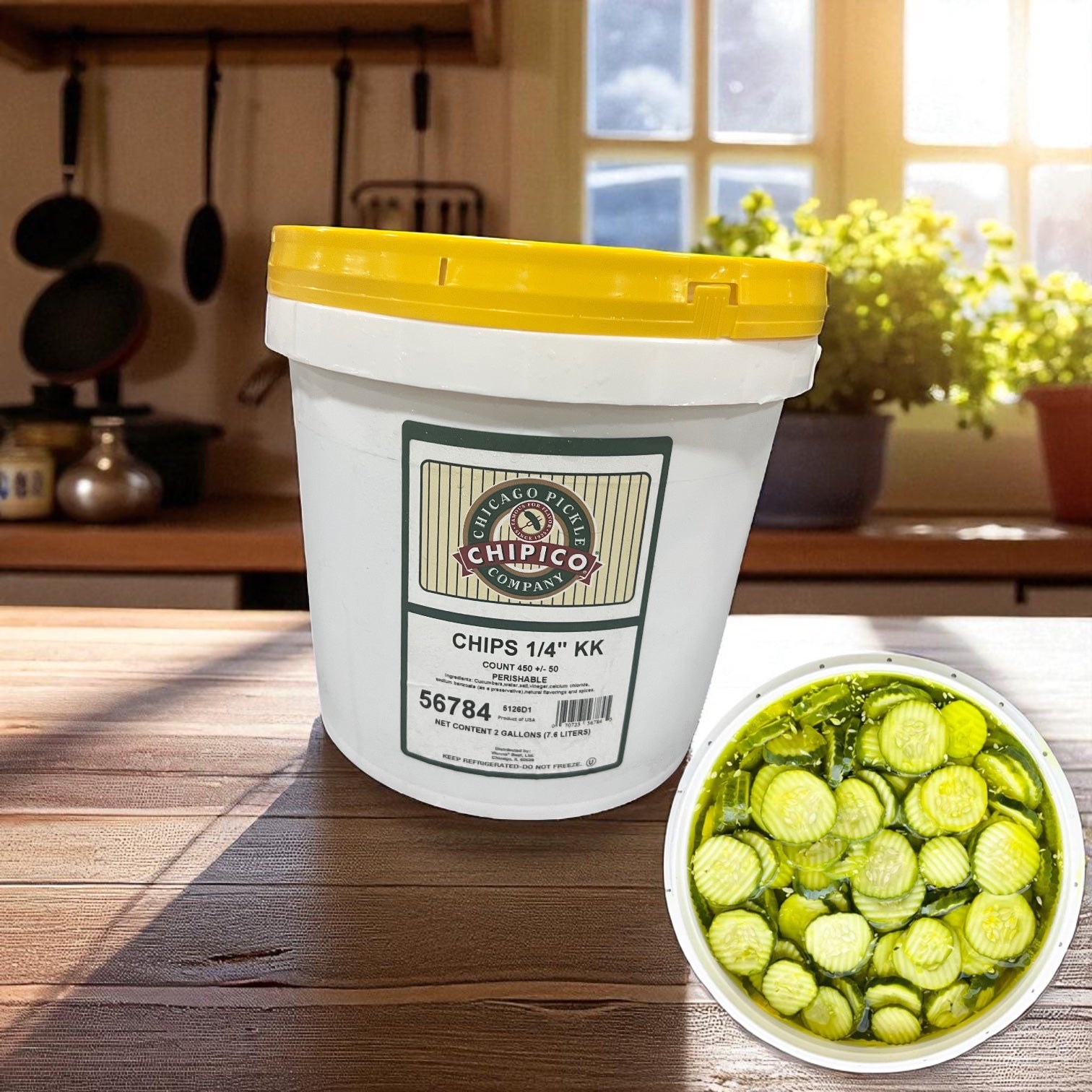 A white plastic bucket labeled "CHIPS 1/4'' KK" sits on a kitchen counter, with a bowl of Vienna Beef Chipico Kosher Dill Chips (2-gallon jar, 450 chips) in the lower right corner.