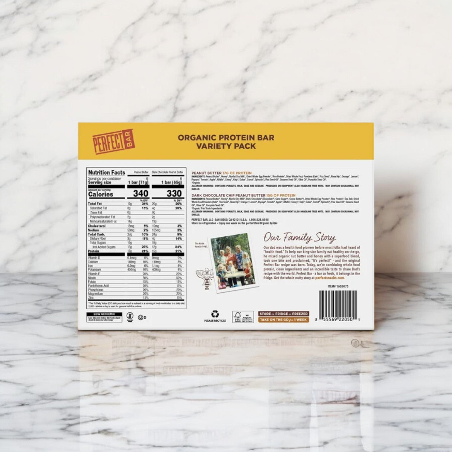 A box of Perfect Bar Refrigerated Organic Protein Bar Variety Pack is displayed on a marble surface, highlighting its nutritional information. The back features a family photo, an engaging story, and emphasizes its superfood ingredients for a nutritious snacking choice.