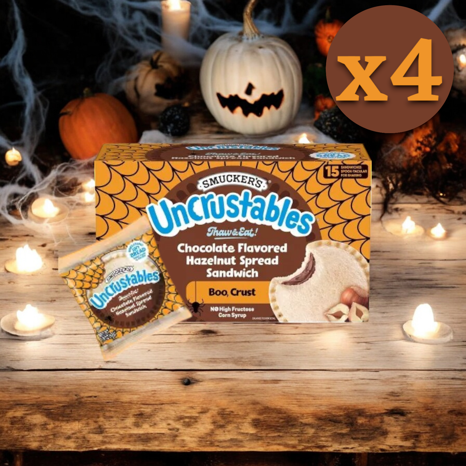 A box and single package of Uncrustable Smuckers Sandwich, Chocolate Flavored Hazelnut Spread Sandwich (15 Count, 4 Pack) on a wooden table adorned with Halloween decorations, perfect for on-the-go snacking. Text indicating "x4" in the top right corner.