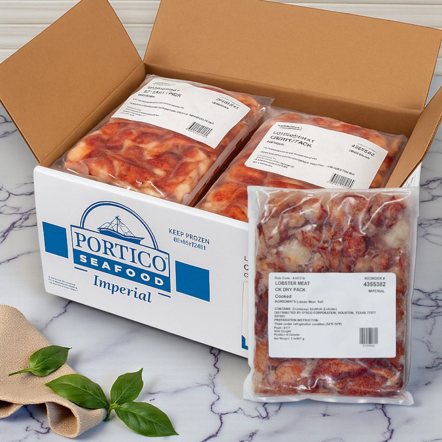 A cardboard box labeled "Easy Lunches" with several vacuum-sealed packs of Maine Lobster Meat Claw Knuckle Dry (6 packs, 2 lbs each, 12 lbs total) on a marble surface, next to two basil leaves.