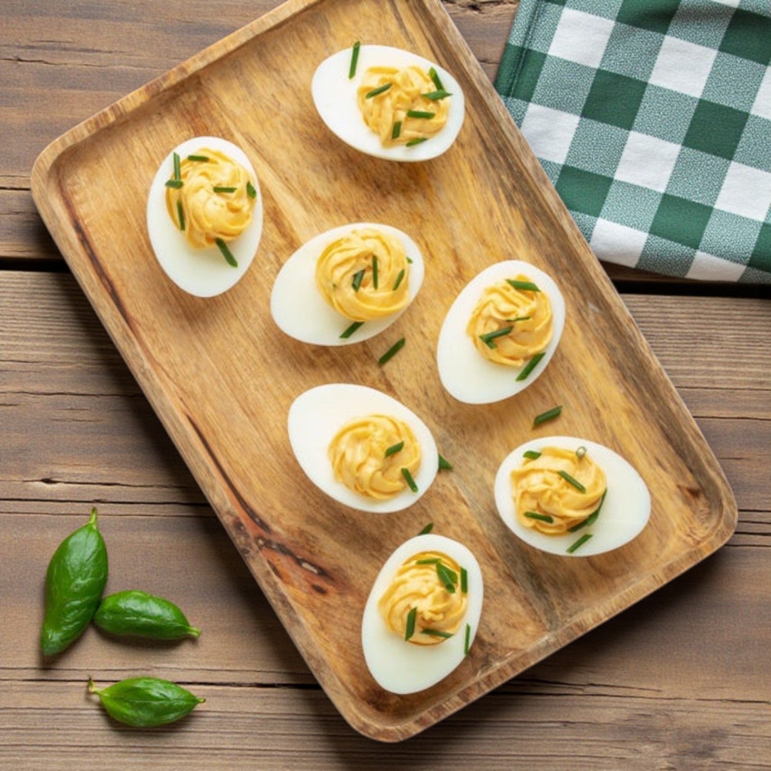 A wooden tray holds eight deviled eggs made with Sysco’s Wholesome Farms Classic Eggs, Hardcooked & Peeled, Dry Pack – 12/12 ct, topped with chives—an ideal choice for eye-catching foodservice presentations.
