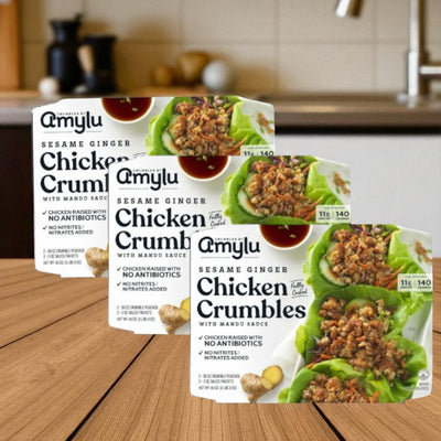 Three packs of Amylu Sesame Ginger Chicken Crumbles, 46 oz each, are shown on a wooden kitchen surface.