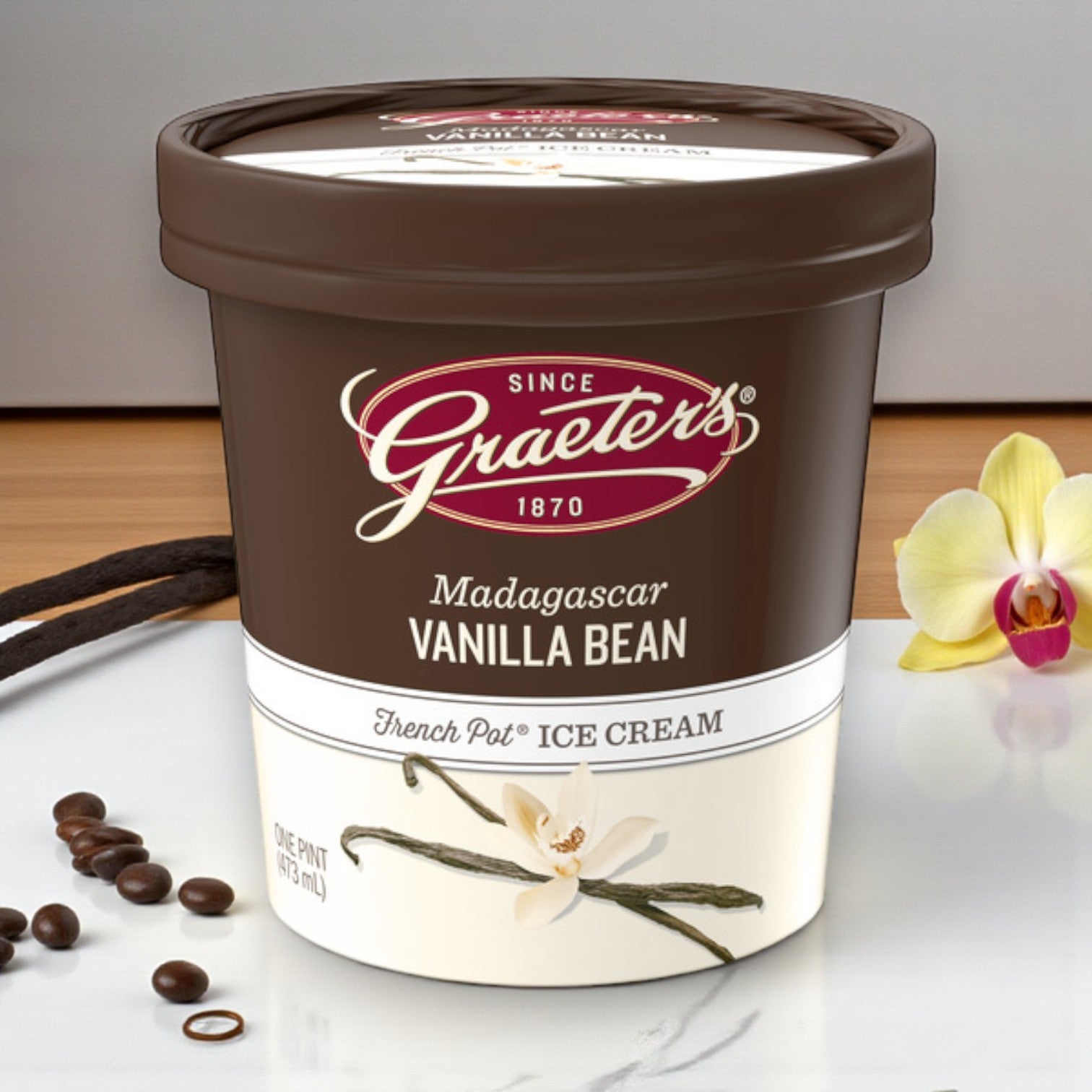 A 6-pint combo pack of Graeter’s Craft Ice Cream sits beside vanilla beans, a vanilla flower, and coffee beans on a table.