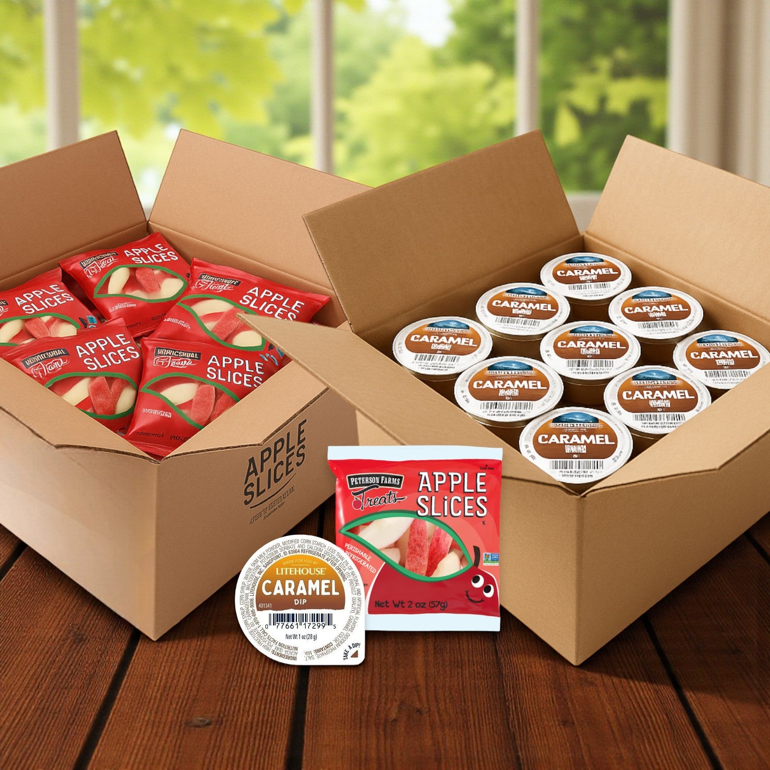 Two open boxes from Peterson Farms sit on a table: one contains Fresh Apple Slices and Caramel Dip Combo packs (100 each), the other holds single-serve caramel cups. A window with greenery is visible in the background.