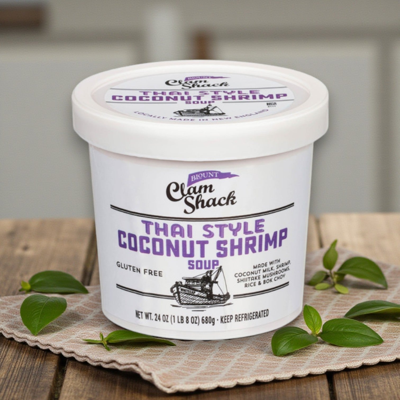 A set of four 24 oz tubs of Blount Clam Shack Premium Seafood Soup Combo from Blount Fine Foods is displayed on a wooden surface with basil leaves, highlighting gourmet seafood soups that elevate New England flavors.