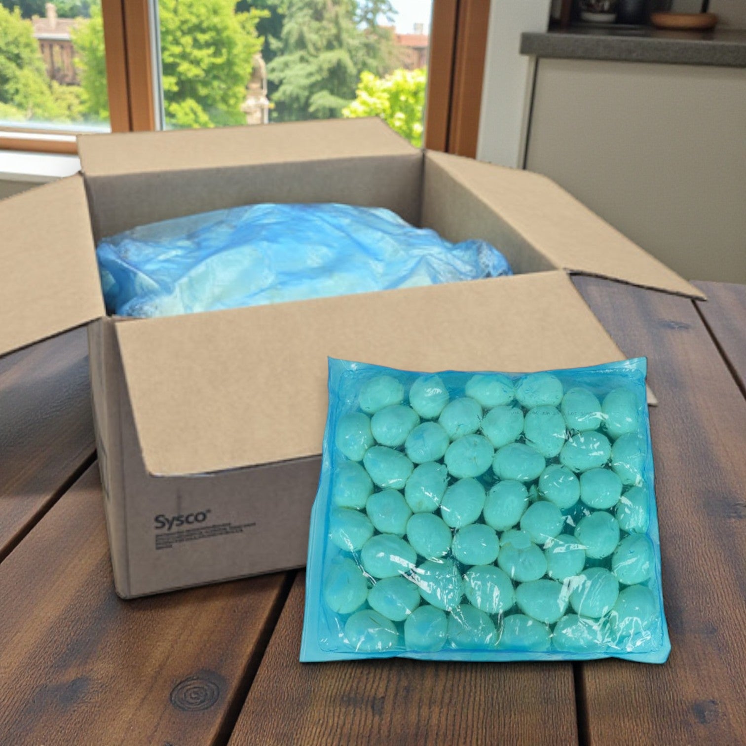 A cardboard box with a blue liner sits on a table; in front, a sealed pack of Sysco Wholesome Farms Imperial Cage-Free Hard-Cooked Peeled Eggs (Dry Pack), 4/5 lb, is displayed.