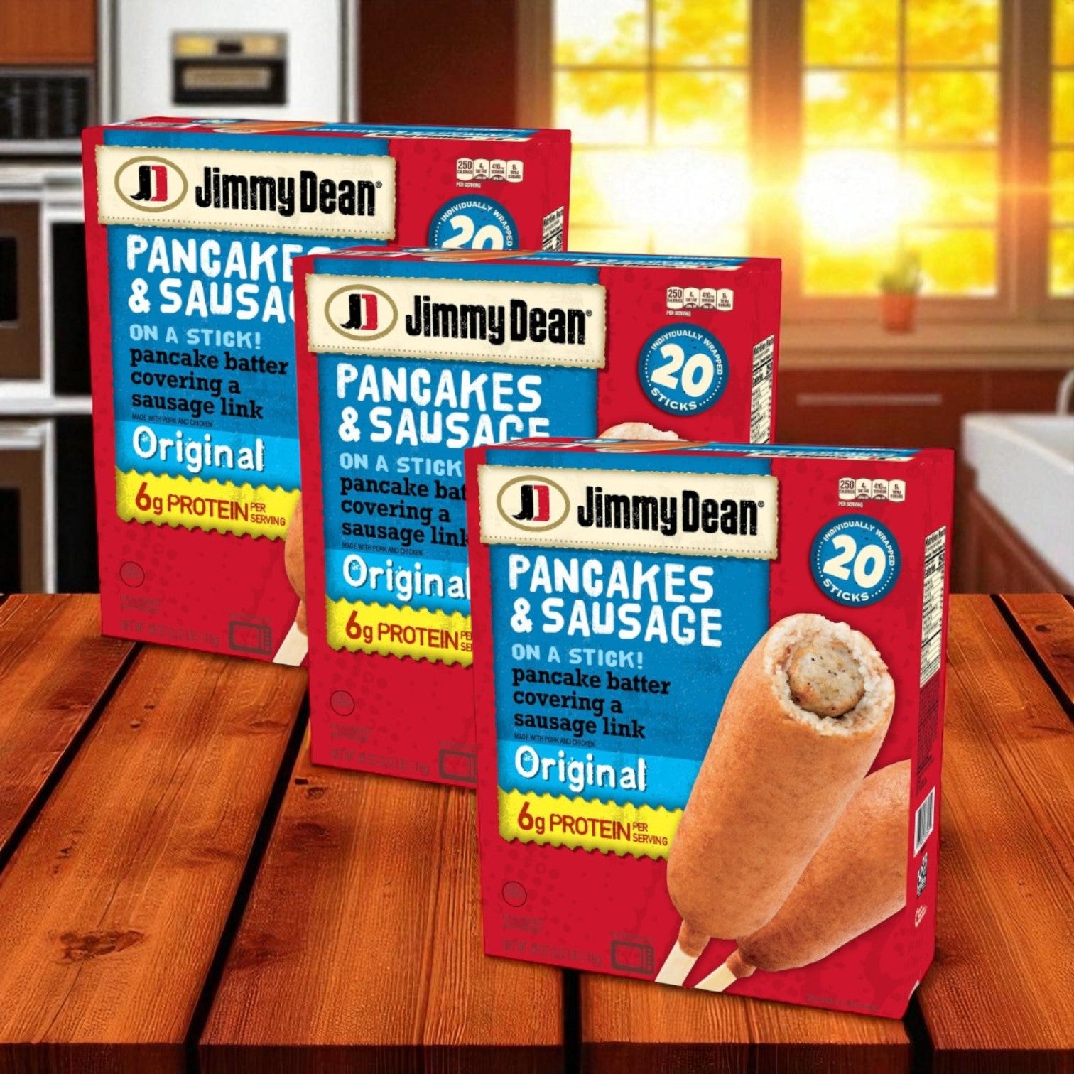 Three boxes of Jimmy Dean Original Pancake and Sausage on a Stick, Frozen, 20 ct-3 Packs are arranged on a wooden table with a sunlit kitchen in the background.