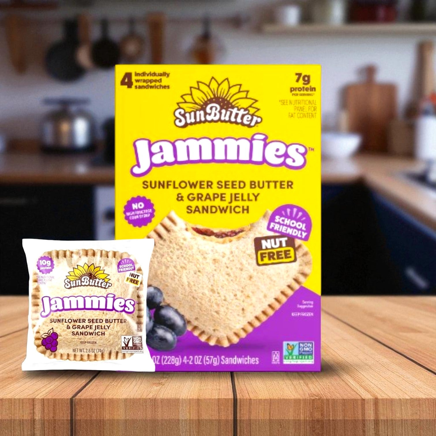 A Sunbutter Sunflower Seed Butter & Grape Jelly Sandwich 8oz 4-count box is displayed on a wooden kitchen surface, highlighting nut-free, crustless snacks made with sunflower seed butter and grape jelly.