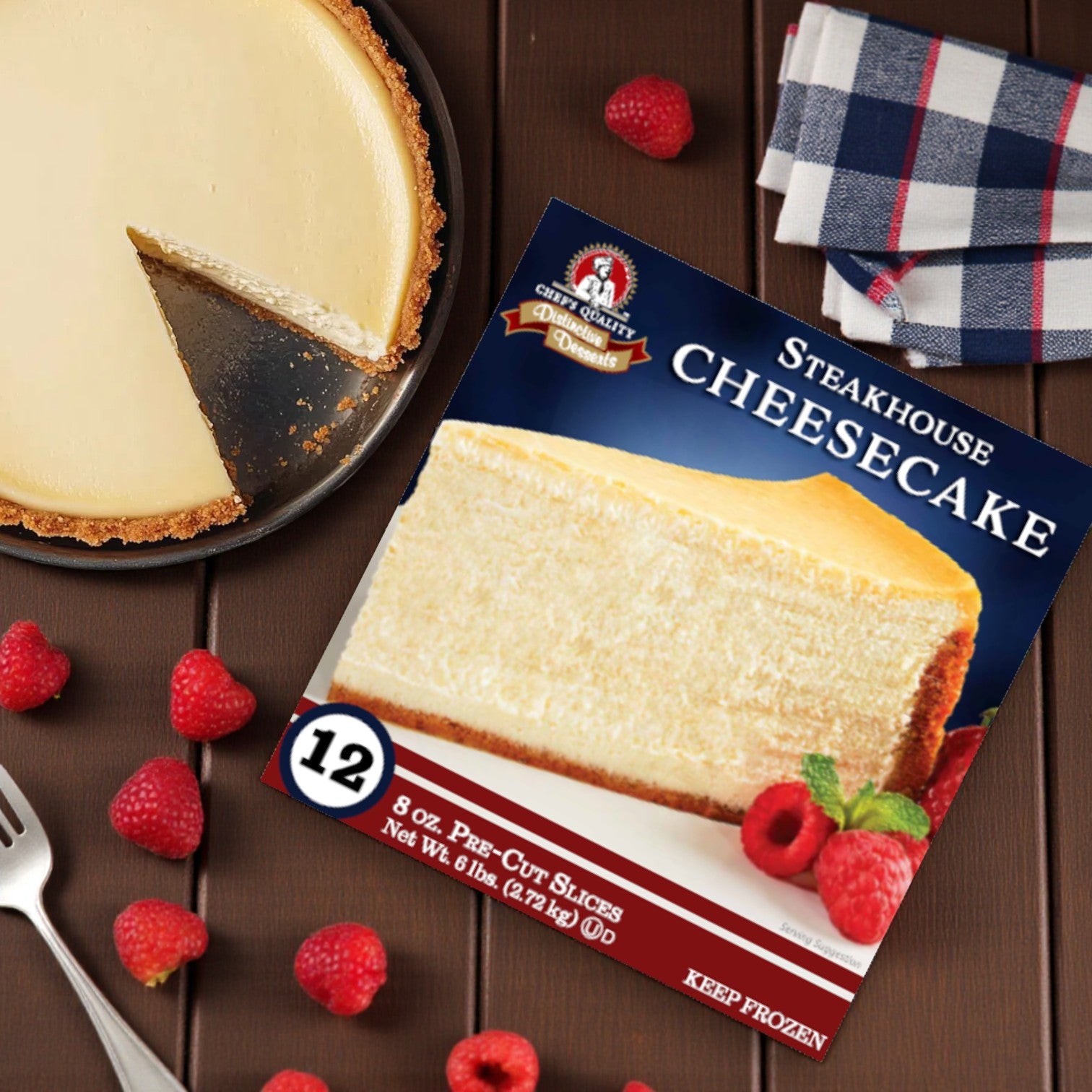 A Frozen Chef's Quality - Steakhouse Style Cheesecake by Easy Lunches, with one of its 12 slices missing, sits next to its box on a wooden table with raspberries, a fork, and a plaid napkin.